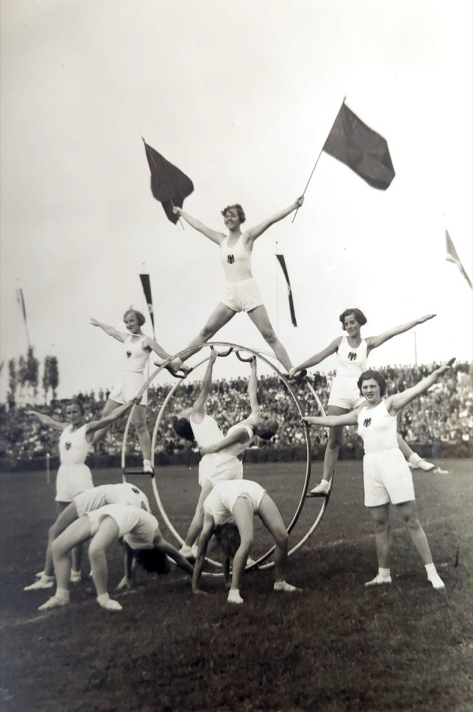 Historisches Foto: Turnerinnen in weißen Trikots auf einem Turngerät mit geschwenkten Fahnen — Bayerisches Landesturnfest Nürnberg 1934